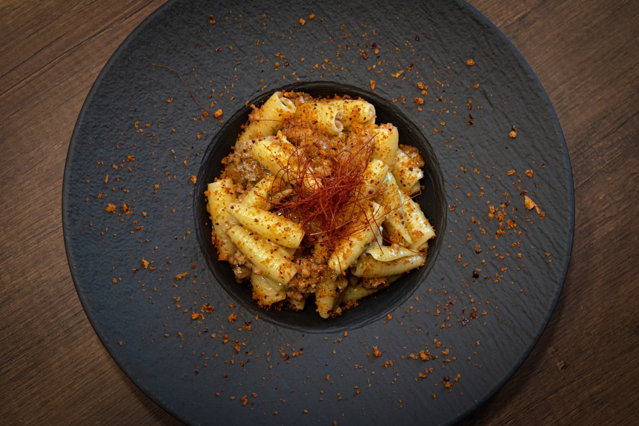 A black plate with a dish of pasta on it